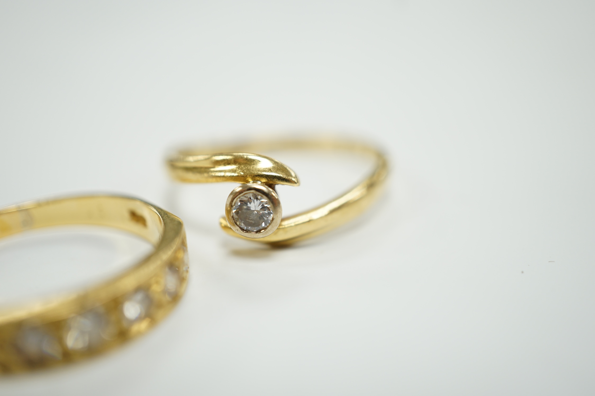 A modern 18ct gold and graduated seven stone diamond set half hoop ring, size O and a similar solitaire diamond ring with crossover setting, gross weight 6.4 grams.